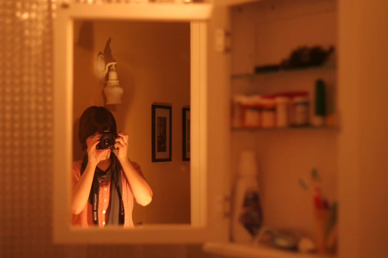 a woman holding a camera taking a picture in the mirror