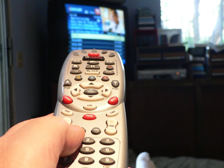 the hand is holding up the remote control to a television