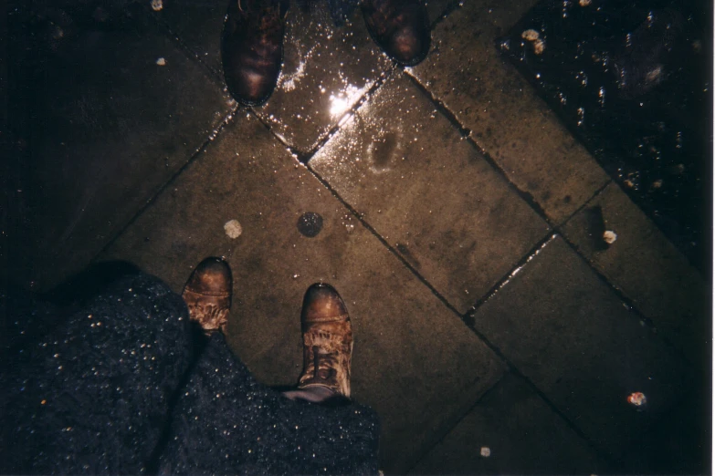 looking down at brown shoes and water on the ground