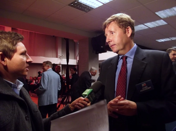 man talks with reporter while other people stand around in the background