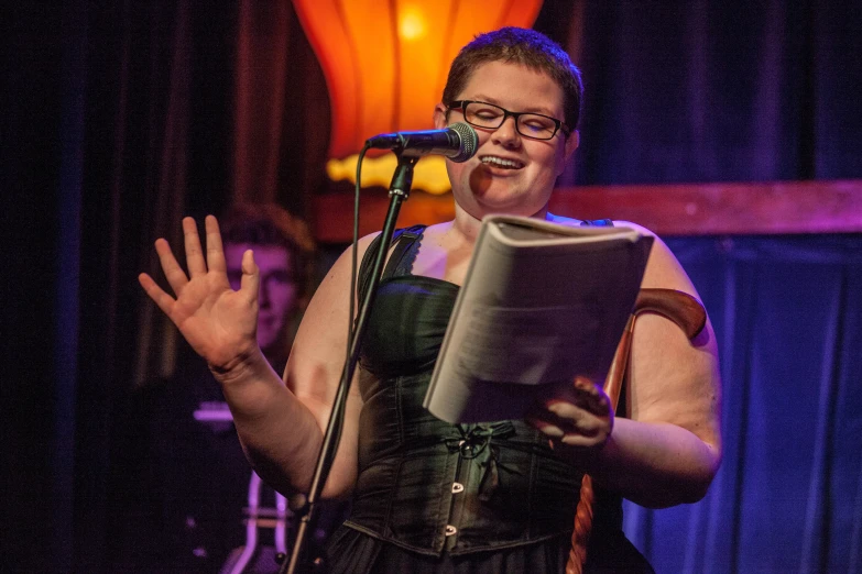 woman standing up while reading book on stage