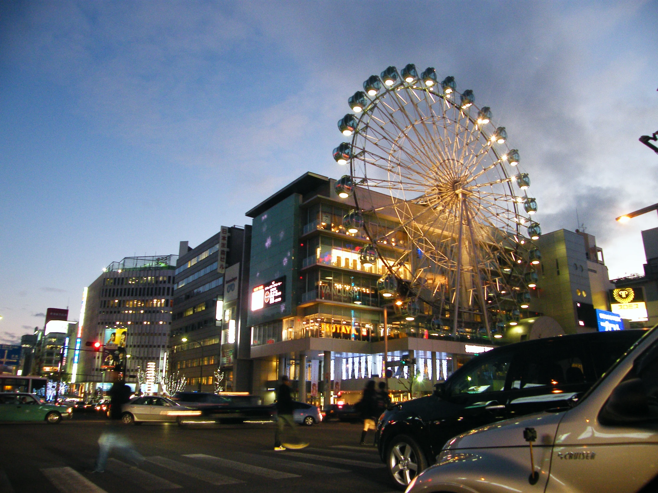 the view of a huge wheel from a busy street