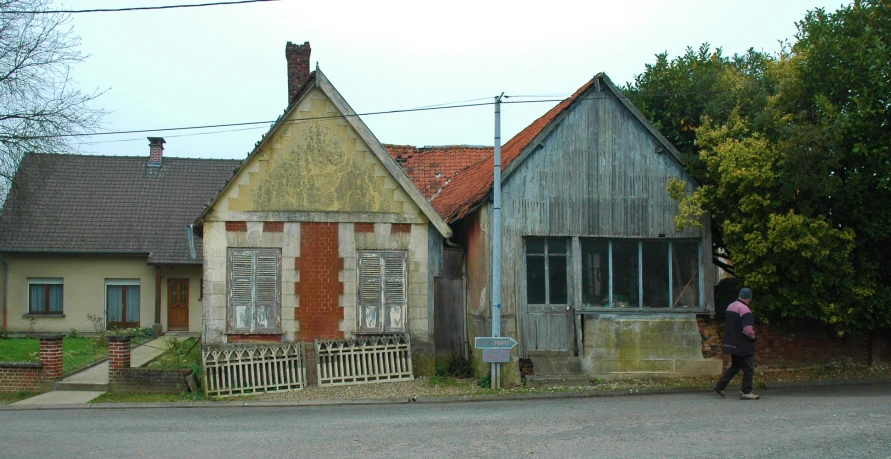 old house with a woman walking past it on a street