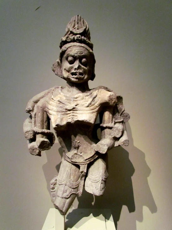 a statue in a corner with a white wall