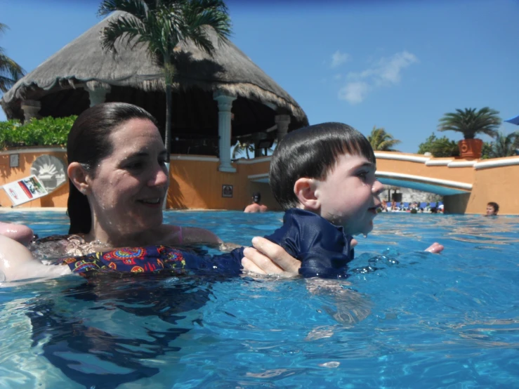 a mother and her child playing in the swimming pool