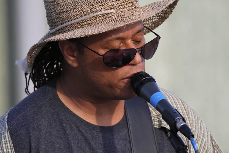 a man with sunglasses and hat on, playing guitar