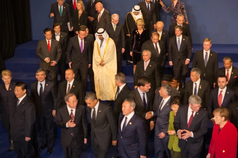 a bunch of well dressed people walking up a blue carpeted steps