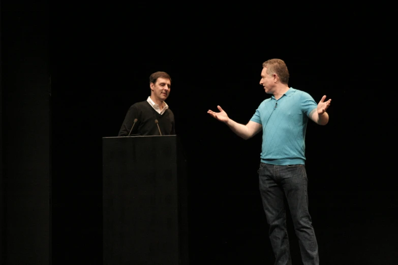 a man on stage speaking in front of another