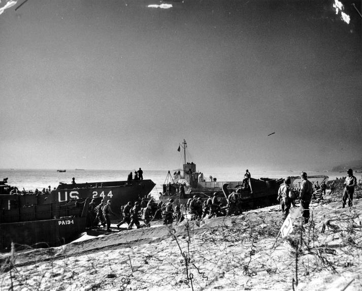 the men are walking near a boat on the beach