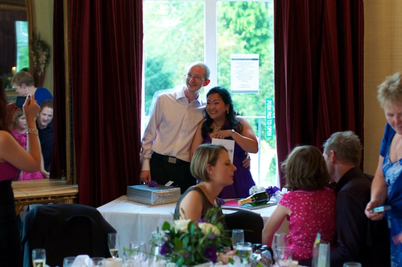 people are standing around tables and smiling at a party