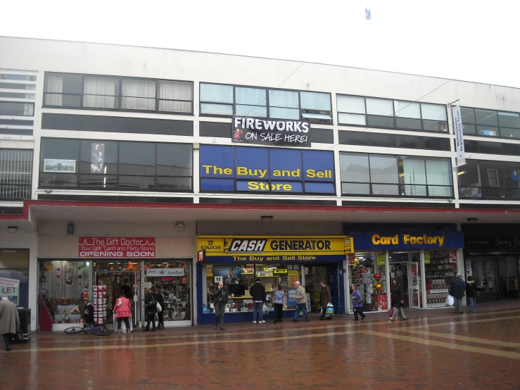 several storefronts, including a fire hydrant, with shops and people walking on the sidewalk