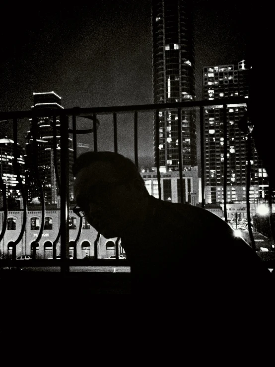 the man is staring out over the city at night