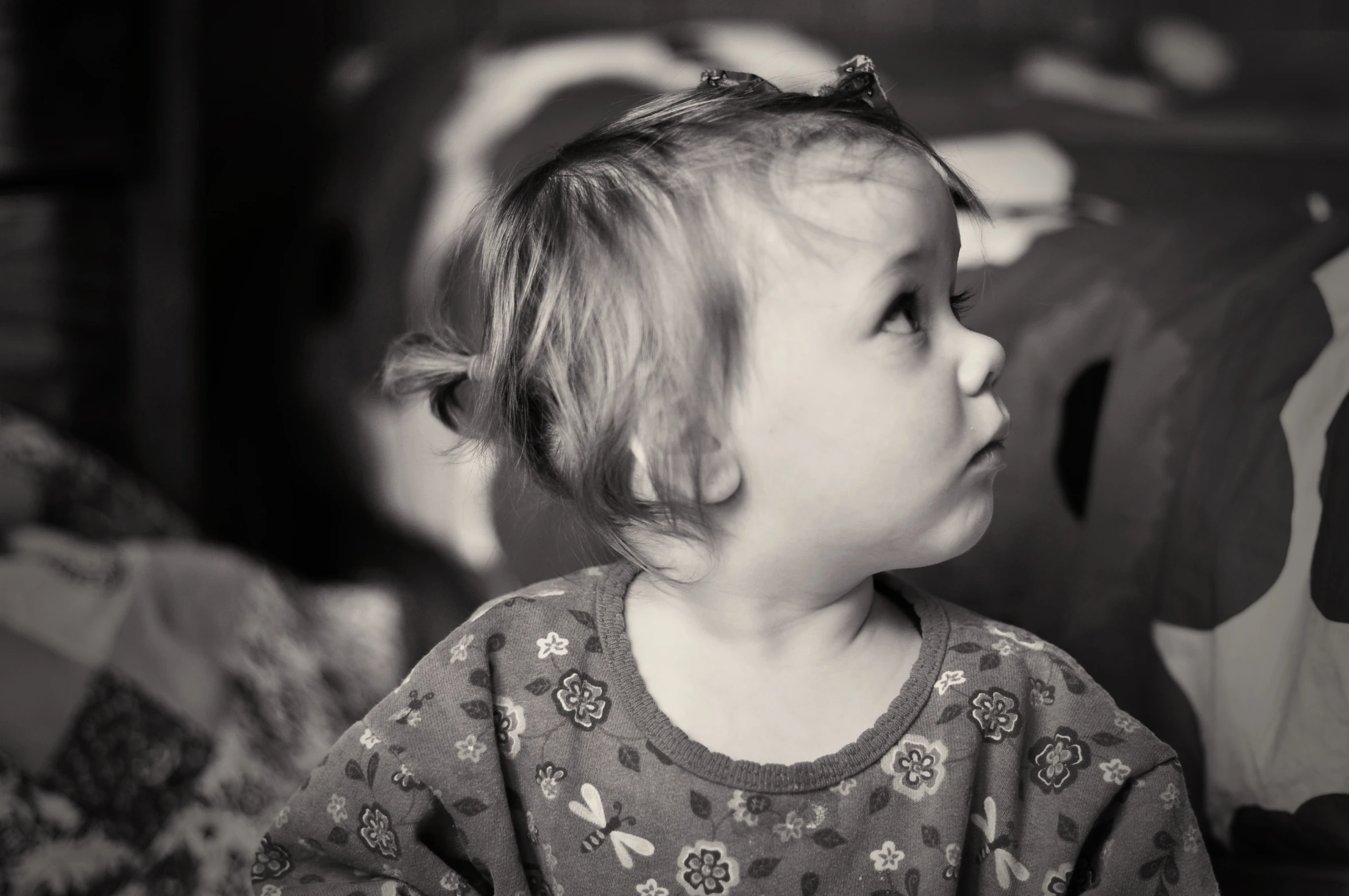 a small toddler sitting on a bed staring