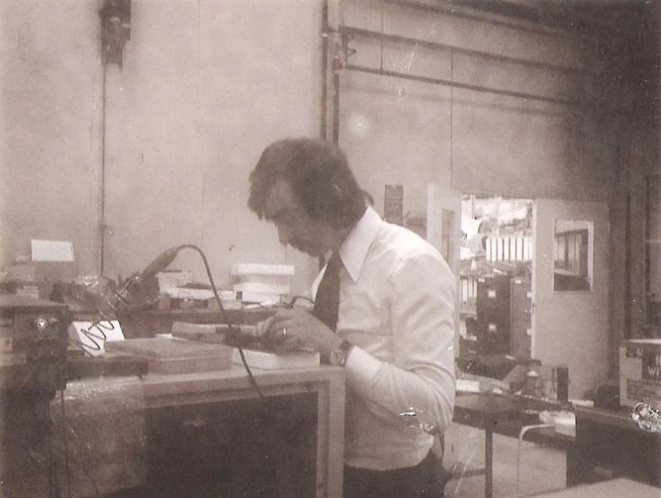 a man in shirt and tie working on soing on the table