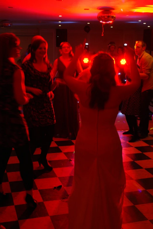 a young woman in a long gown on a dance floor with her arms in the air