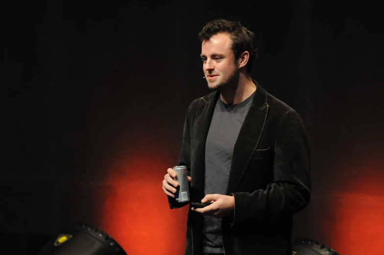 the man is holding a beer on stage