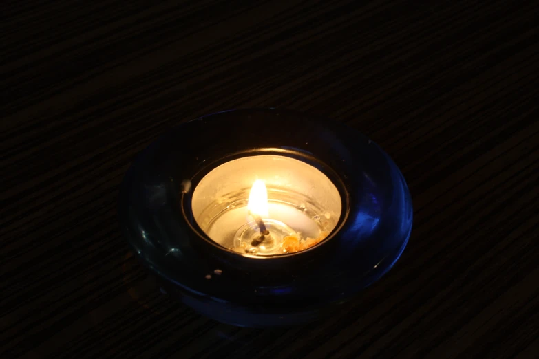 a lit candle burning inside of a blue glass bowl