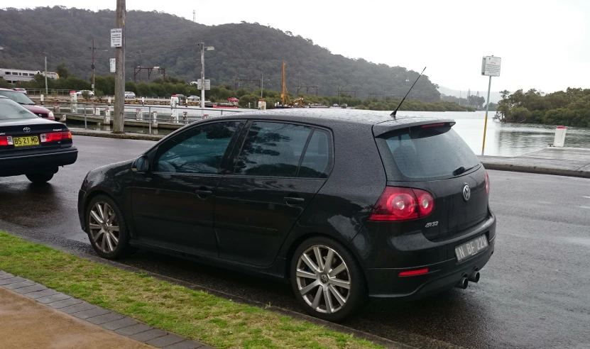 two cars parked on a wet road with mountains in the background