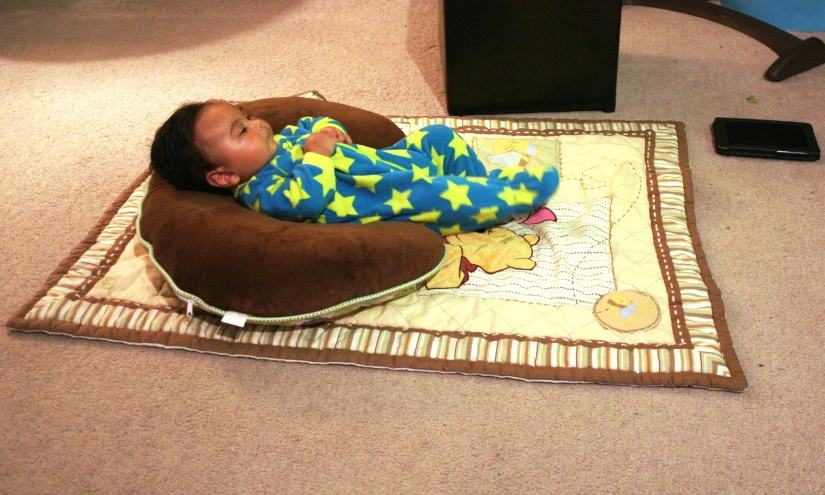 a baby on his back resting in an infant pillow