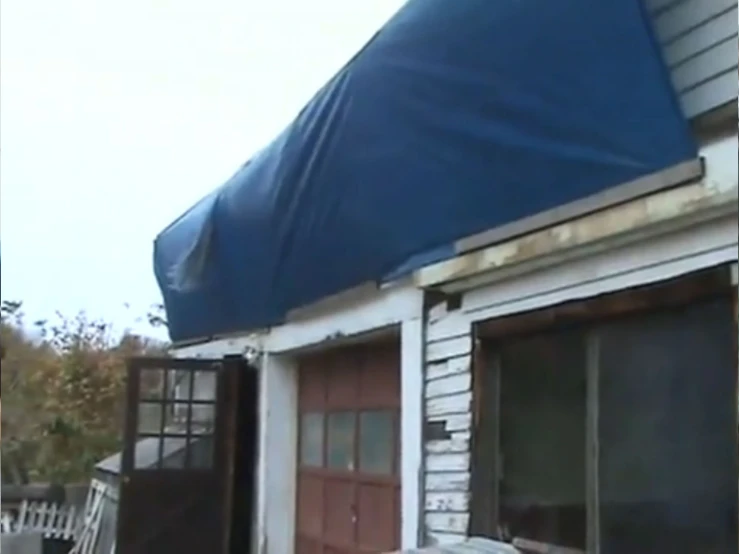 a wooden chair under a tarp outside a house