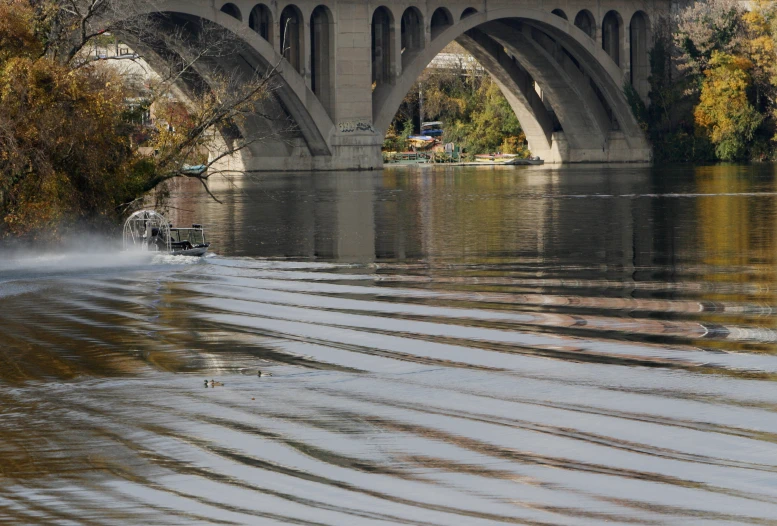 a boat traveling on a lake under a bridge