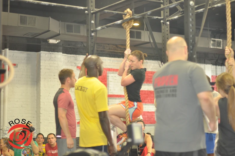 several people are watching an instructor and a trainer hold a pole