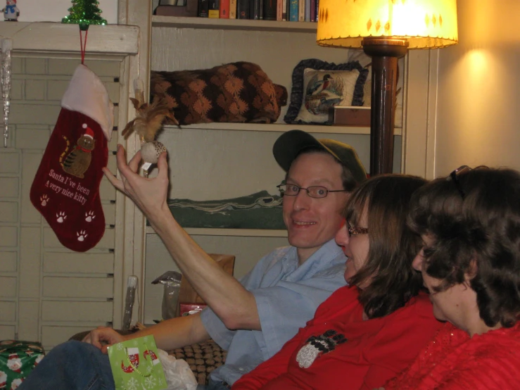 two people holding christmas stockings, and one person holding a cat