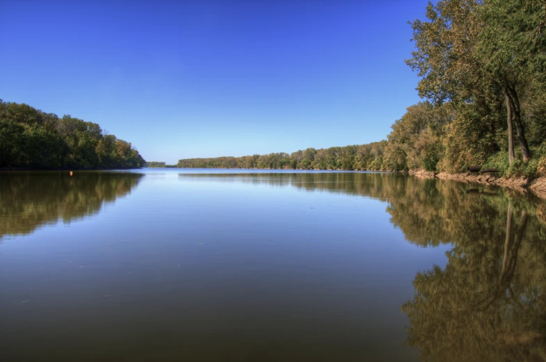 a body of water with trees and a boat in the background