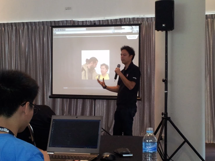 a man standing in front of a presentation on a projector