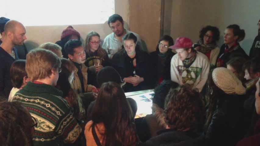 a crowd of people in front of a window looking at a digital device