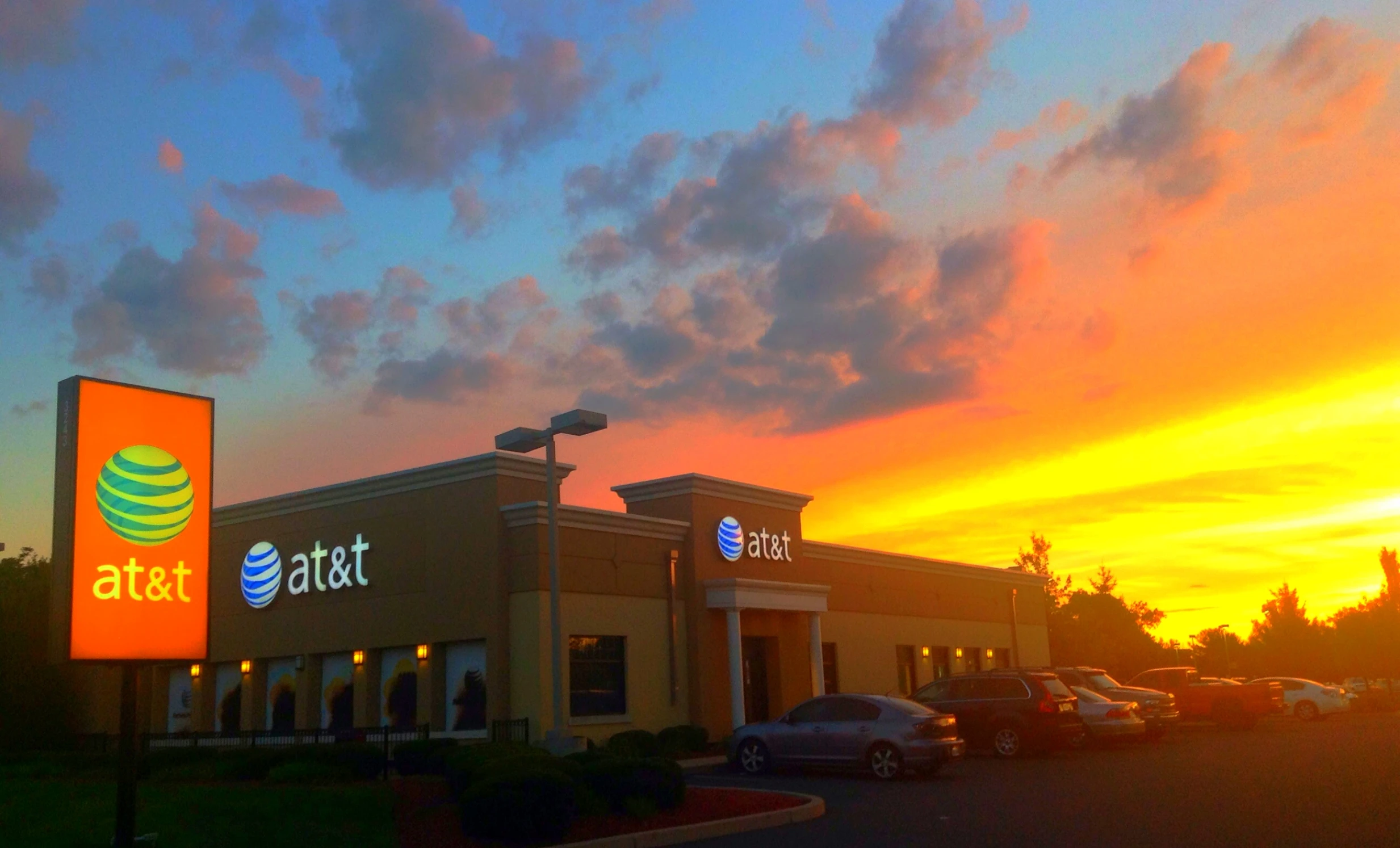 a sunset in a retail center with cars parked in front of it