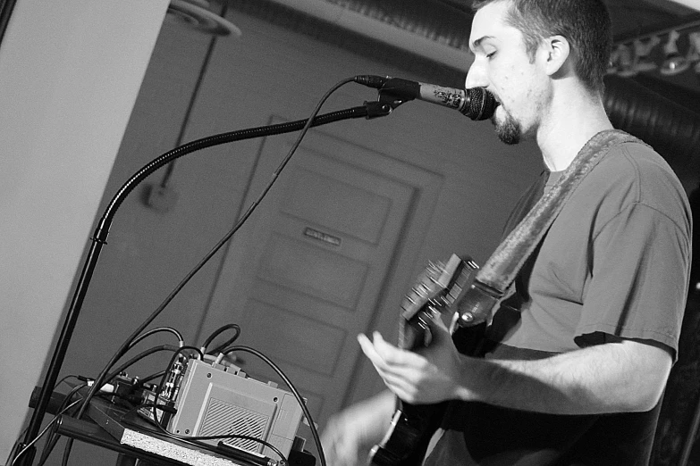 a man that is holding a guitar in front of a microphone