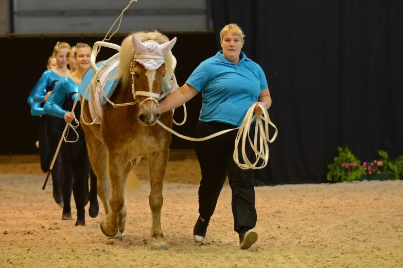 a woman leads a horse with a white ribbon