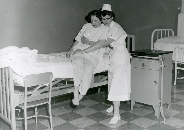 black and white pograph of woman holding baby next to crib