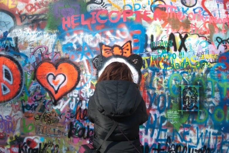 a person standing in front of a wall with graffiti