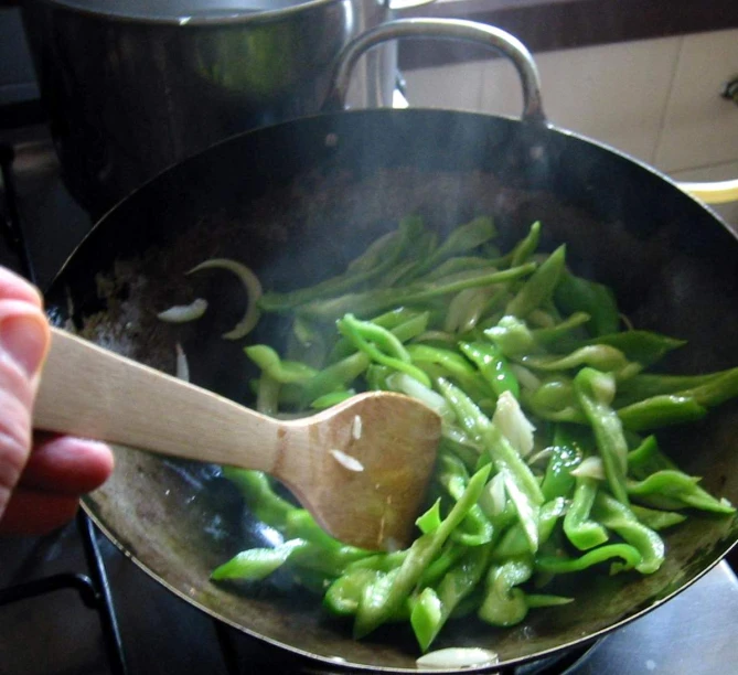 a wok containing asparagus and green peas