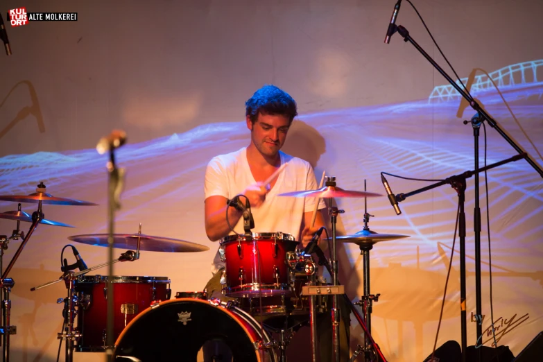 a man is playing drums in front of several microphones