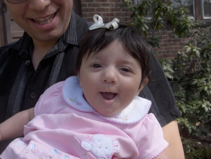 the baby is smiling for the camera while her parents hold him