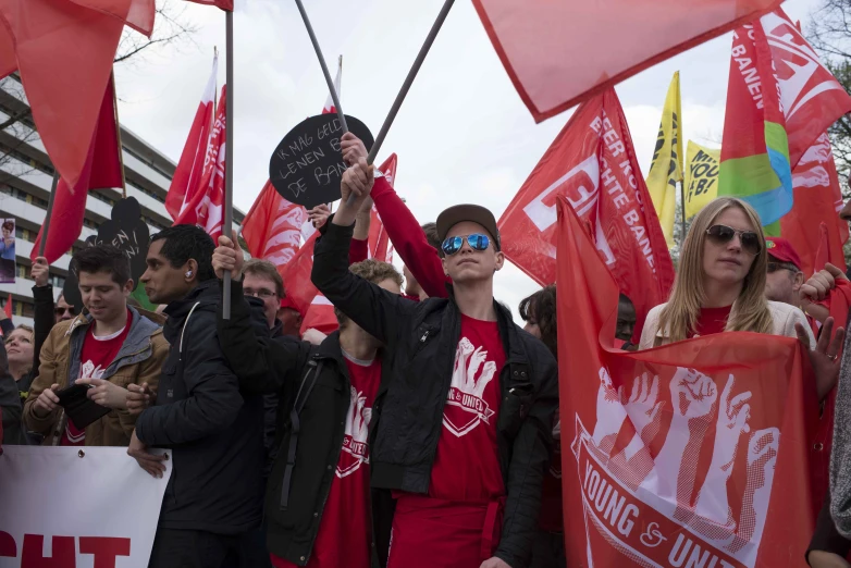 a crowd of people stand behind each other holding up red flags