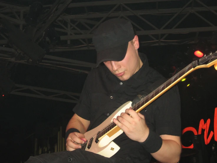 a person in a black hat plays guitar