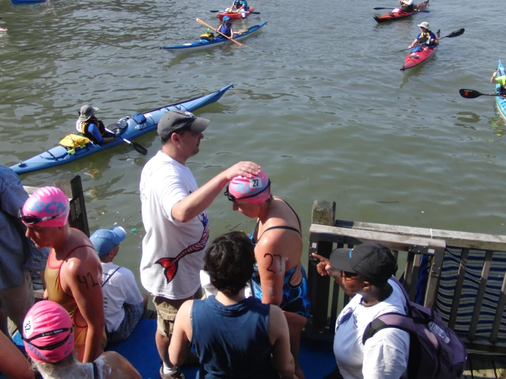 several people watching a man stand in front of row boats