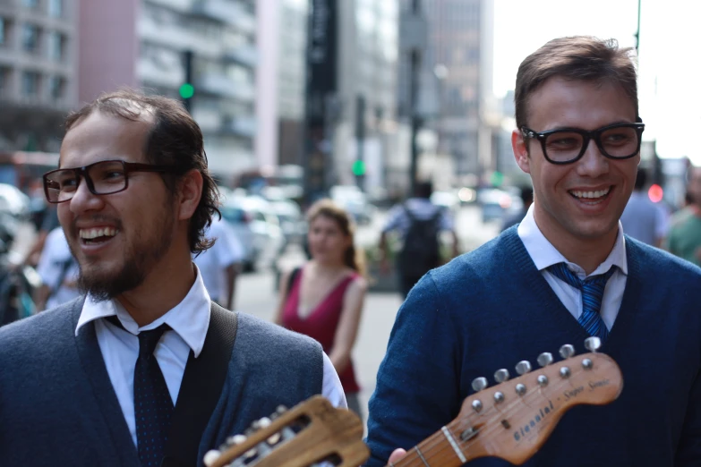 two guys in glasses and a sweater with an electric guitar