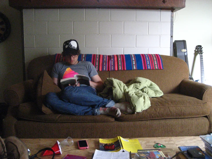a man is laying on a couch reading a book