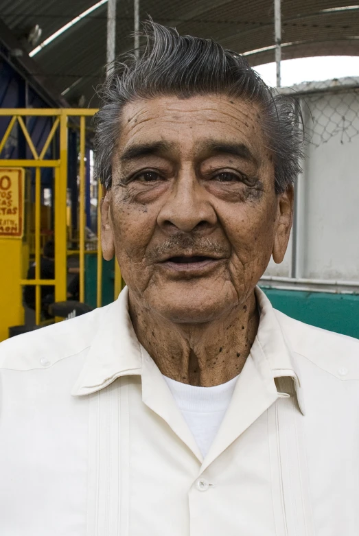 an older man standing in front of a metal structure