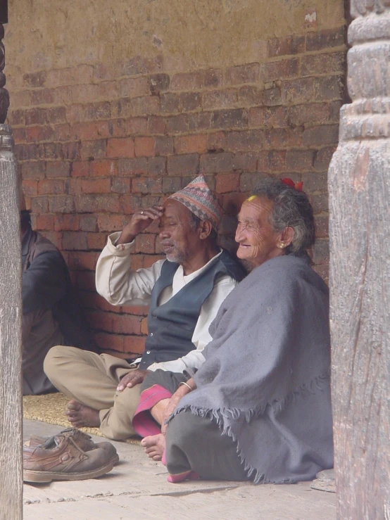 two older people are sitting on a ledge