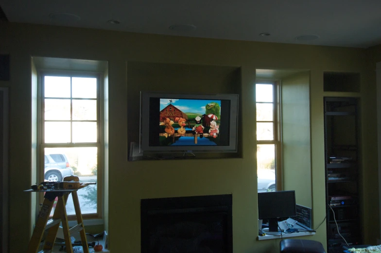 two windows in a room and a television on a wall