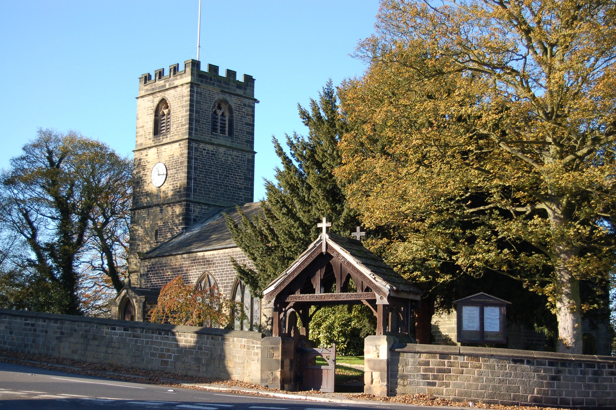 a clock tower and gate stand behind a stone wall