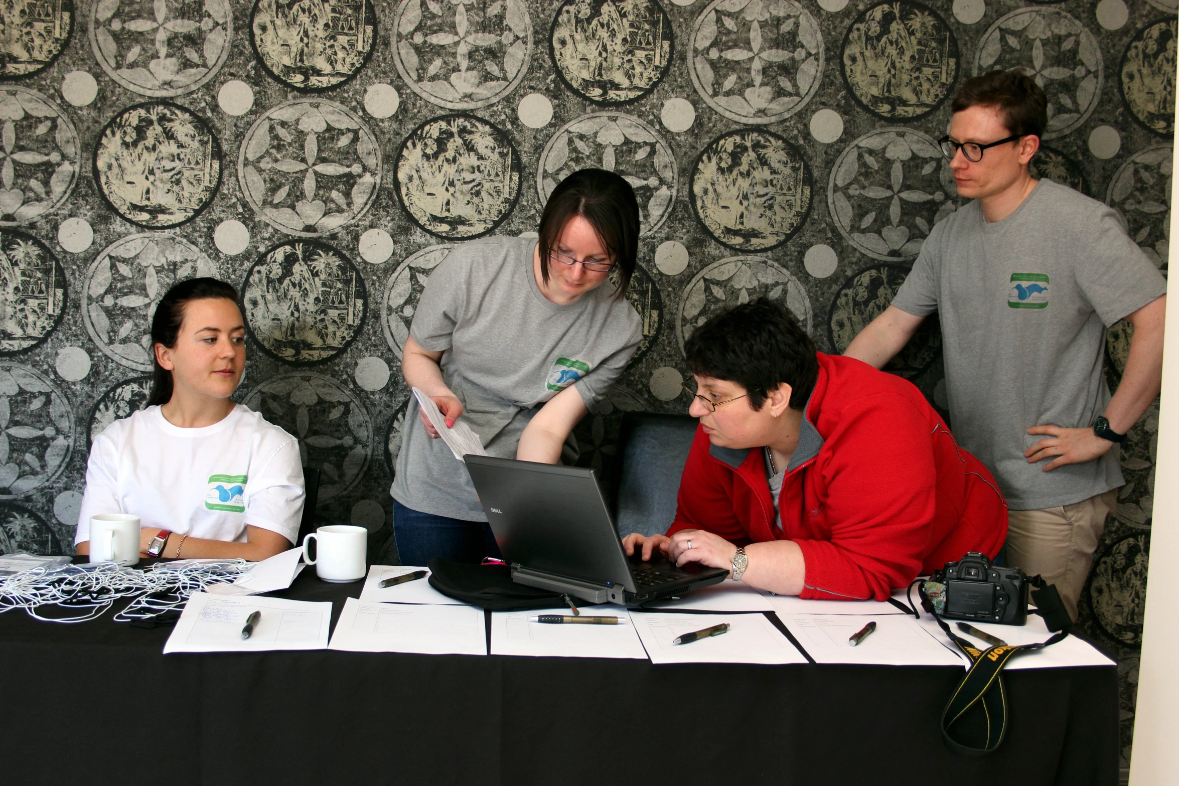 four people around a table with a laptop