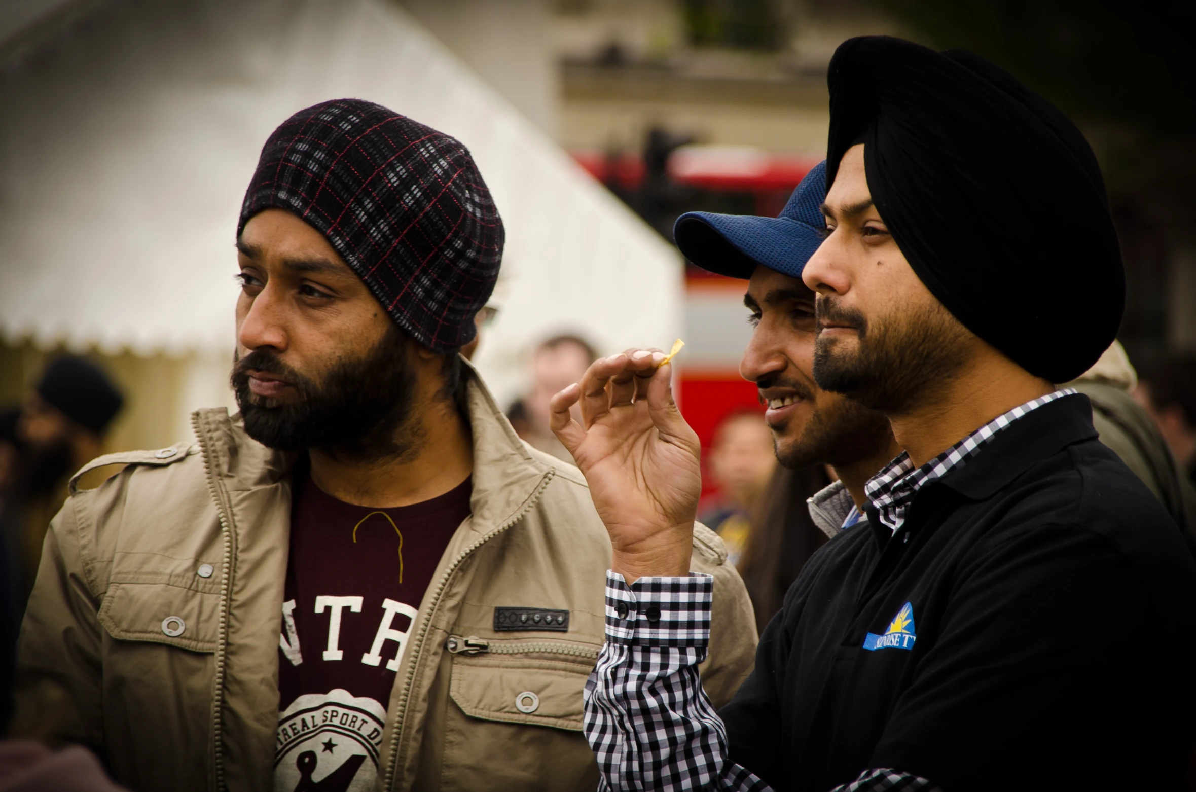 two men are smoking and one is wearing a hat