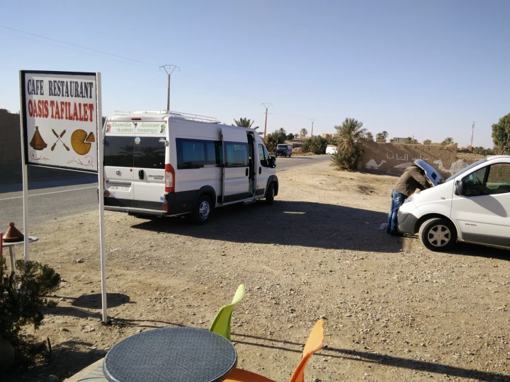 some cars a van and a sign in the middle of a road